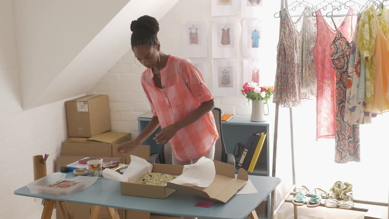 一名加勒比黑人妇女在自家的办公室里打包一件商品视频下载