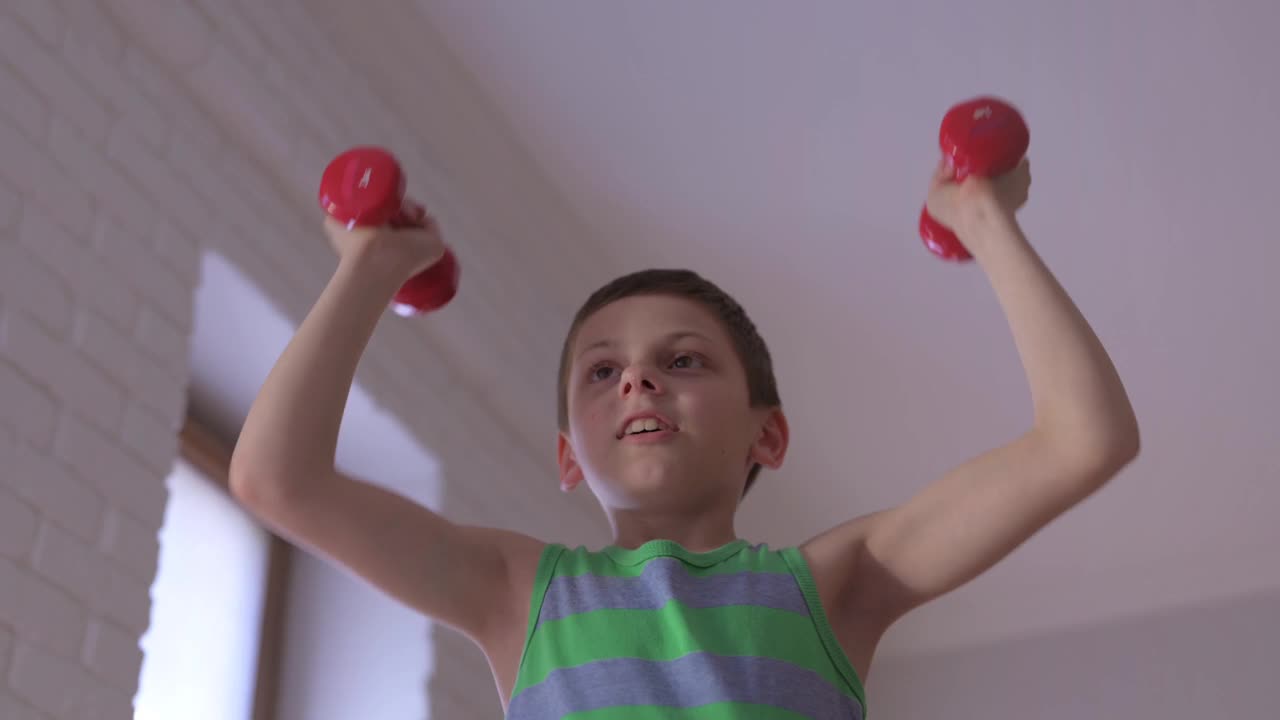 健康活跃的白种人小强壮男孩在室内家庭运动肌肉训练娱乐健身锻炼举哑铃视频下载