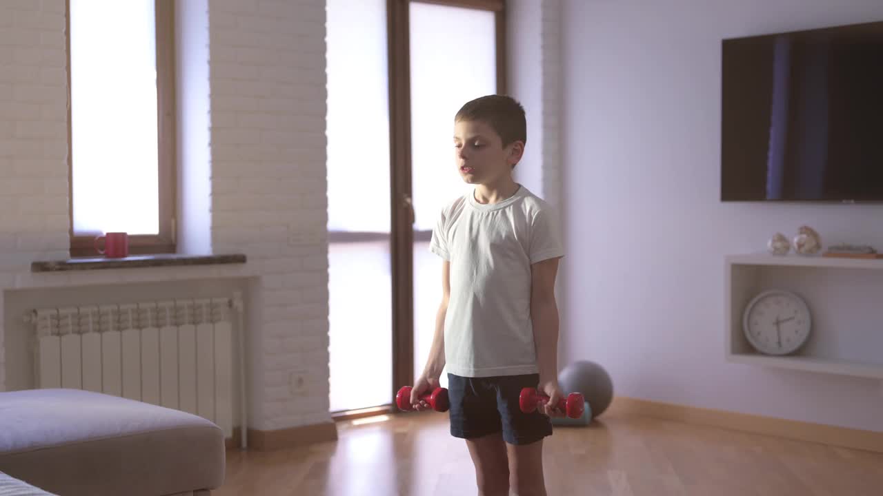 健康活跃的白人小孩在室内训练，娱乐，健身锻炼期间在白色的运动衫举哑铃视频下载