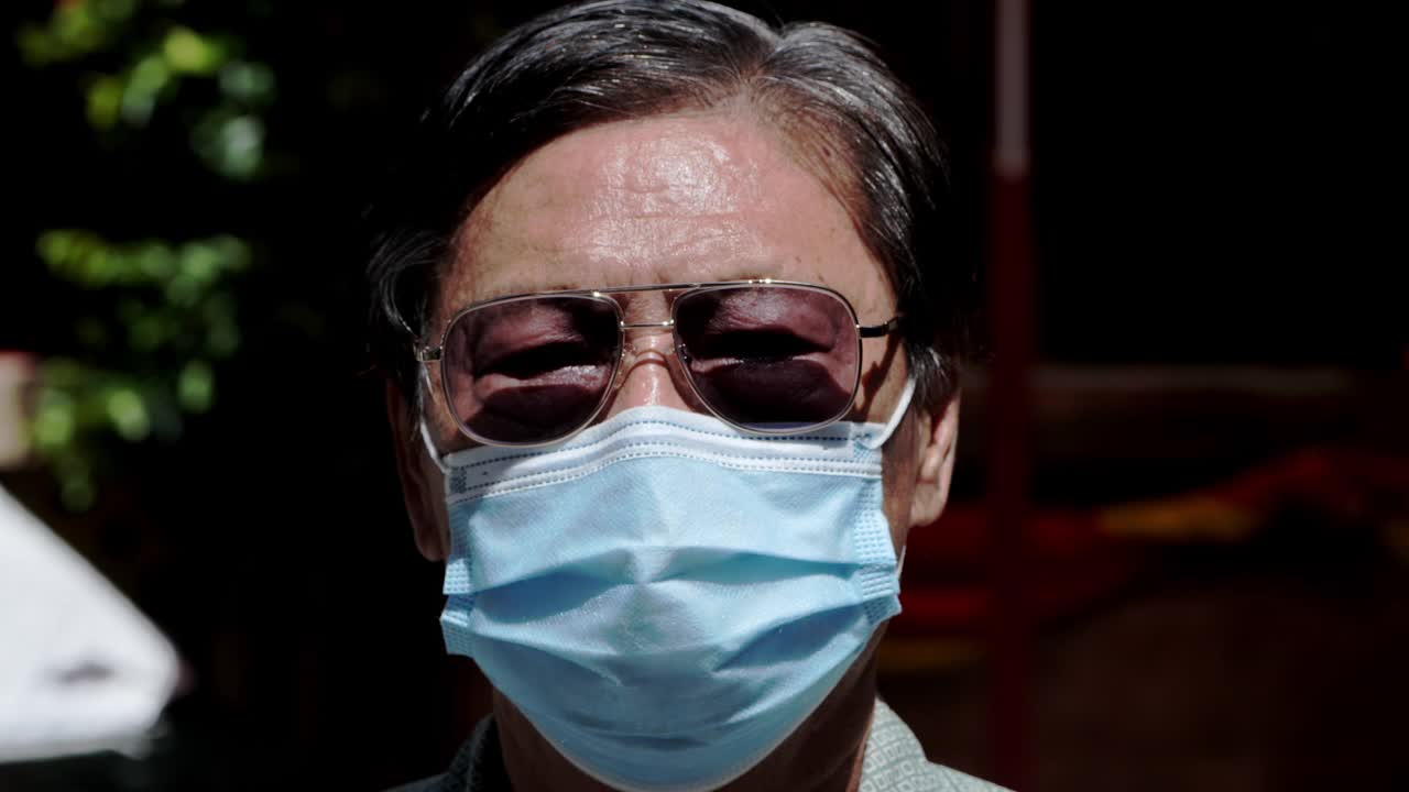 一个戴着口罩的老人在街上的肖像视频素材