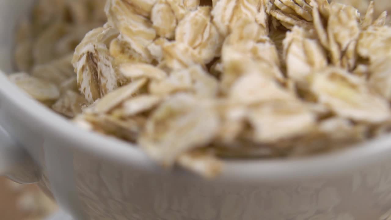 勺子从一只白色的碗里慢动作地舀出生燕麦片。宏视频下载