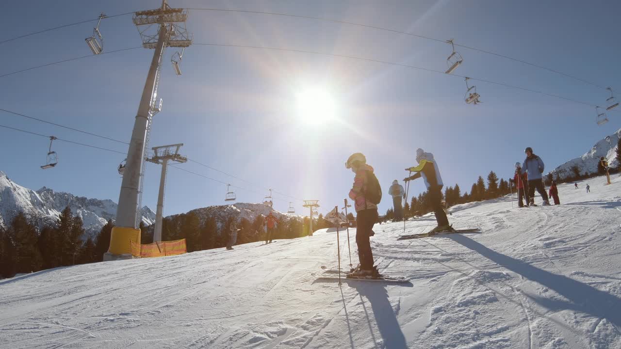 人们在冬季阳光照耀下的斜坡上滑雪视频素材