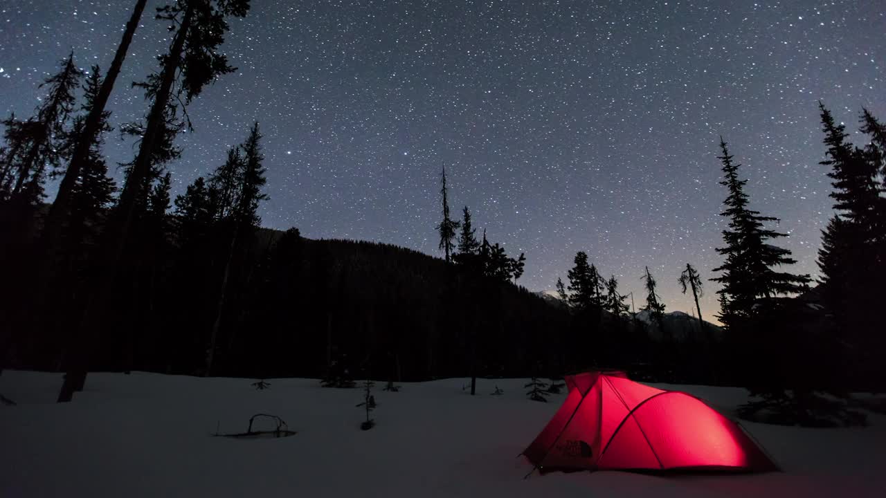 延时锁定拍摄的星空下森林中白雪覆盖的景观上发光的红色帐篷-加拿大不列颠哥伦比亚省视频下载