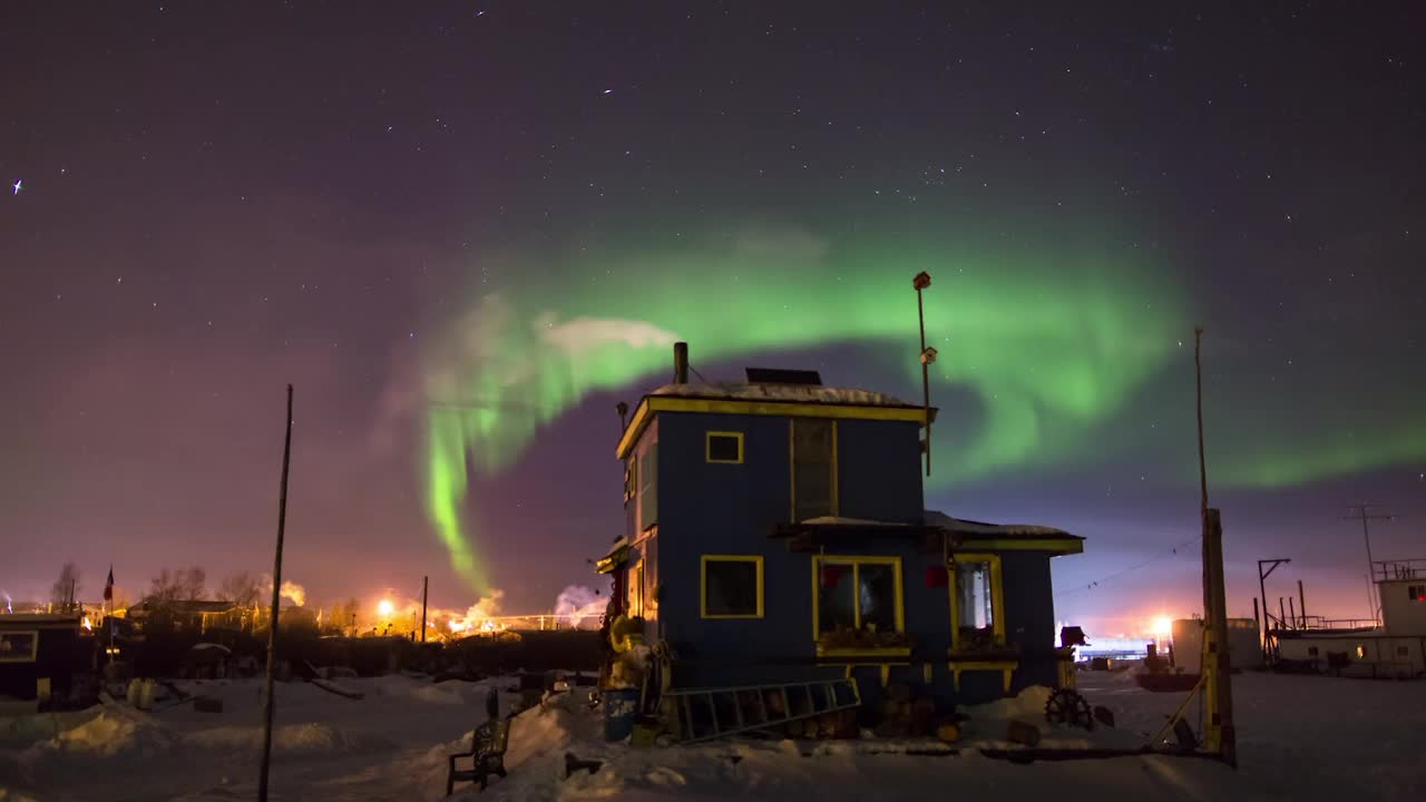 在加拿大不列颠哥伦比亚省的冬季，当北极光在天空中移动时，蒸汽从蓝房子上方的烟囱喷出视频素材