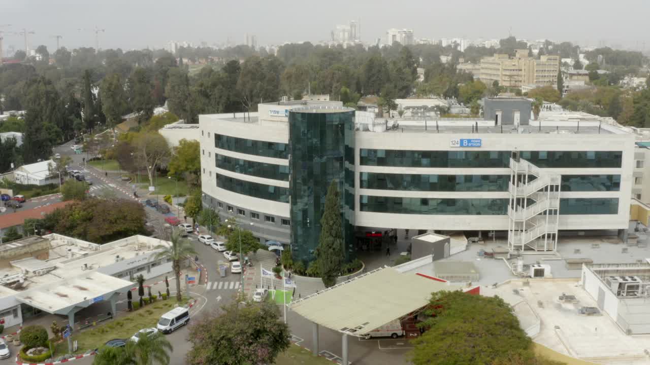 空中拍摄的著名医疗中心与城市的天空，无人机向后飞行在停车场的汽车-特拉维夫，以色列视频素材