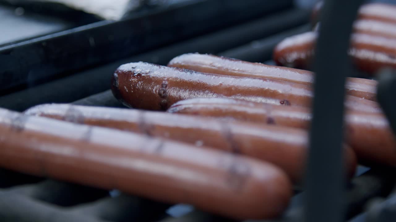 在森林露营时，在火坑烤架上烤着美味的烧焦热狗的特写镜头视频素材