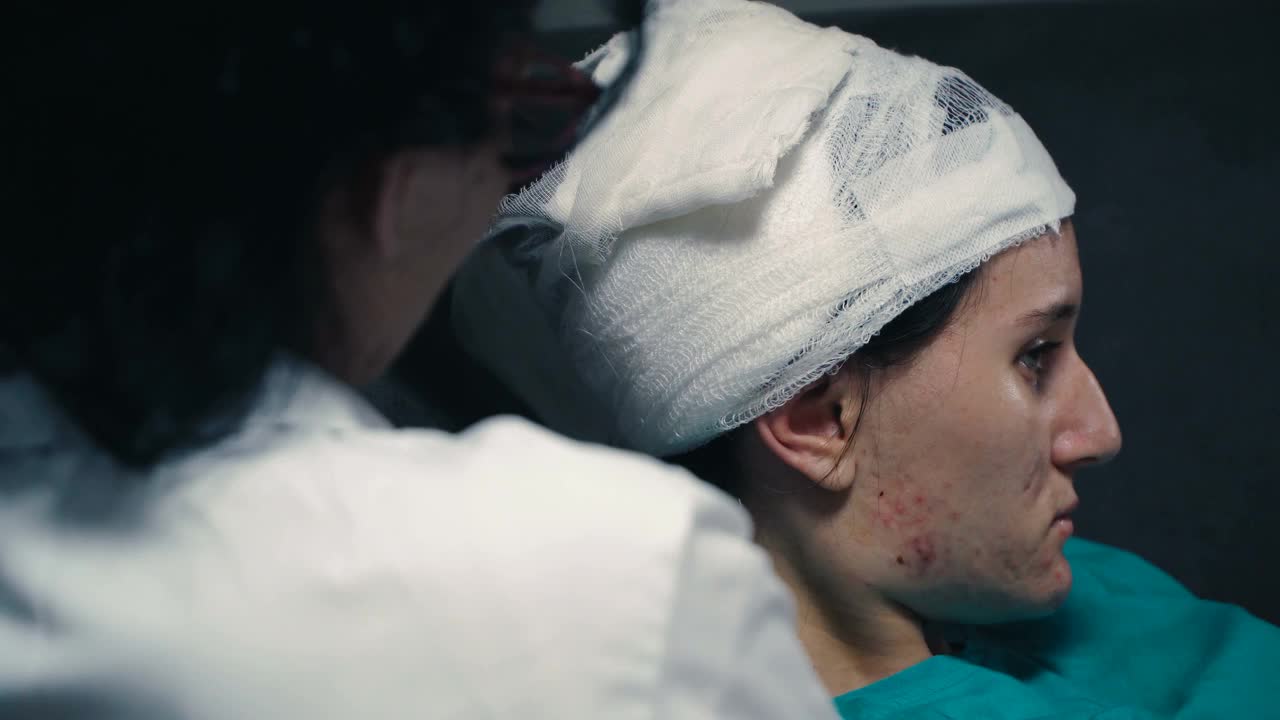 年轻女性头部受伤在医院的治疗。头部用弹性绷带包裹视频素材