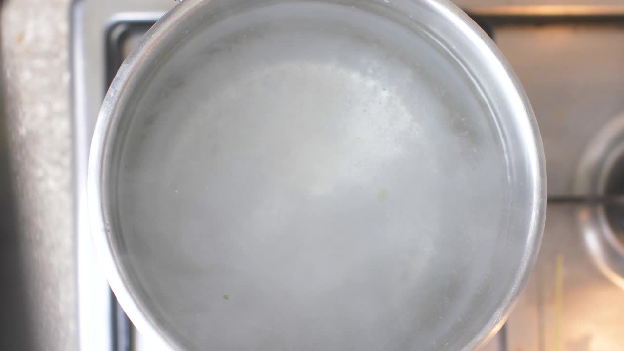 俯视图上的银锅的沸水在厨房炉子上。厨师添加正宗的意大利细面条视频素材
