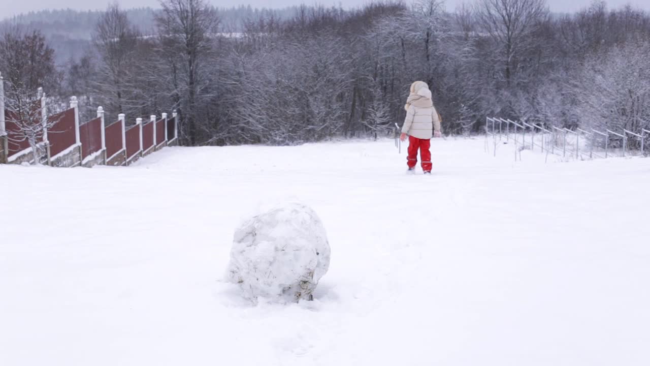 小女孩在雪山上奔跑。在冬天玩。视频下载