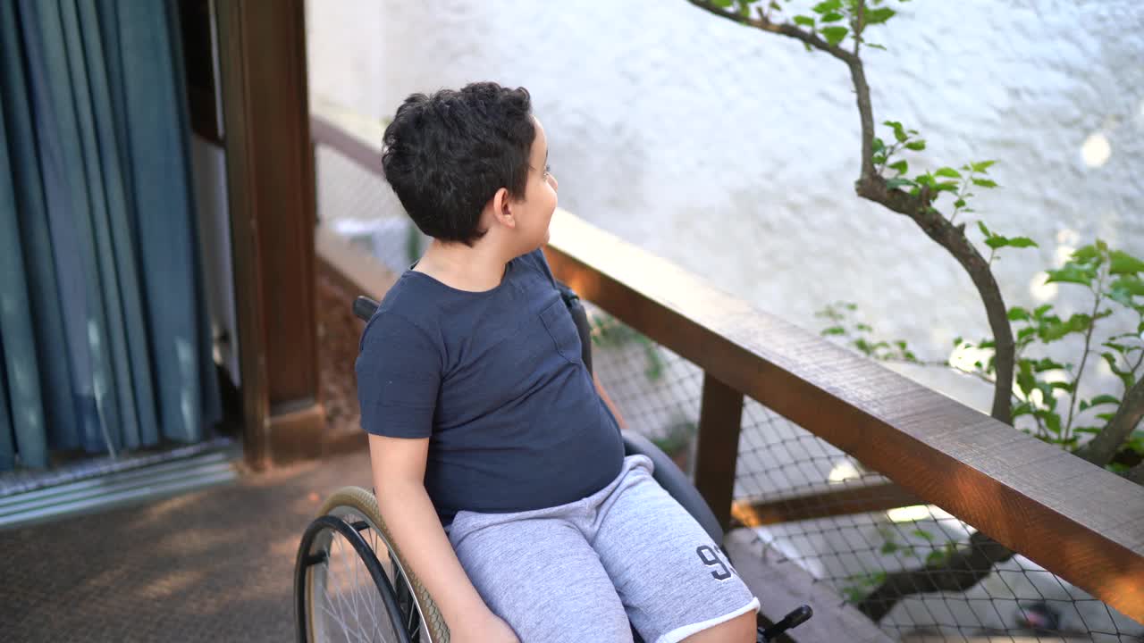 一个坐在轮椅上的男孩的肖像在屋外视频素材