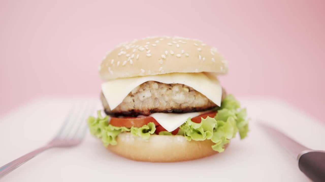 粉色背景的汉堡孤立，快餐概念。视频素材