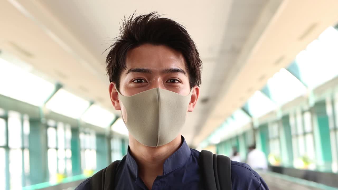 微笑的年轻亚洲男子戴着防护面具的肖像视频素材
