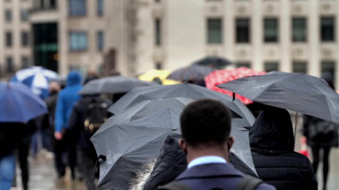在雨中打着雨伞的城市通勤者。视频素材