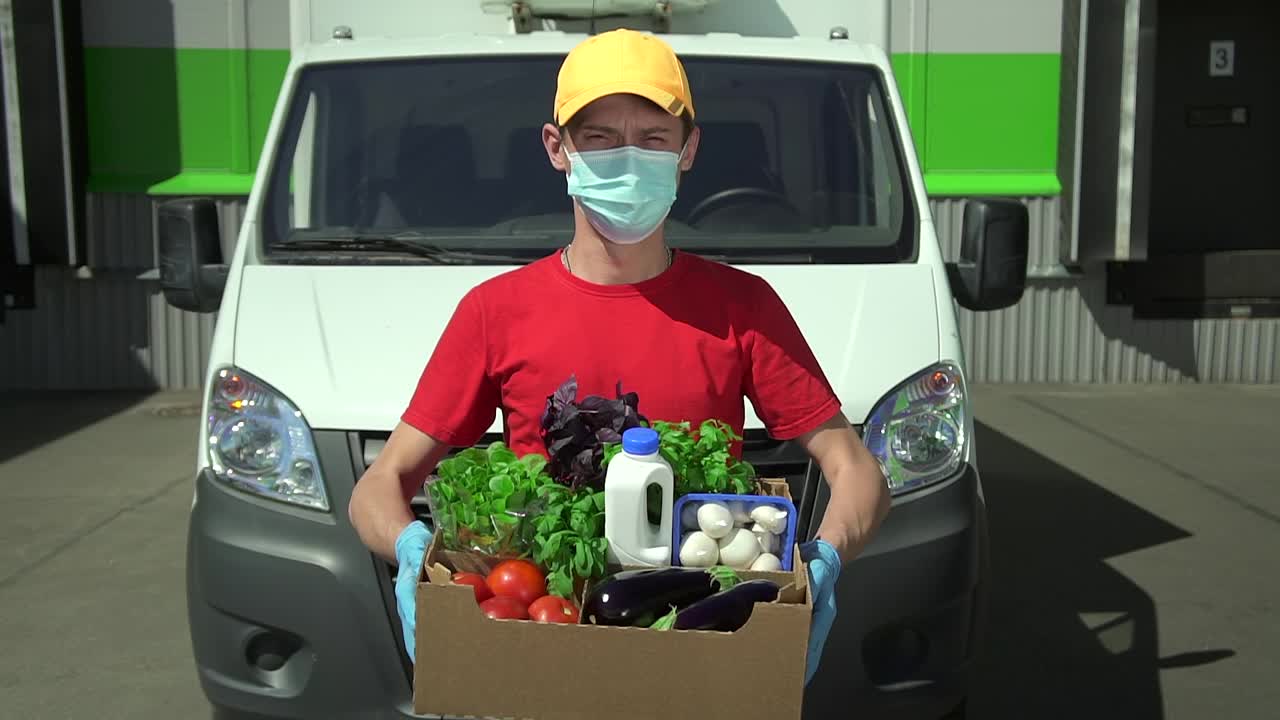 一个年轻人拿着一盒食物，站在户外汽车的背景上视频下载
