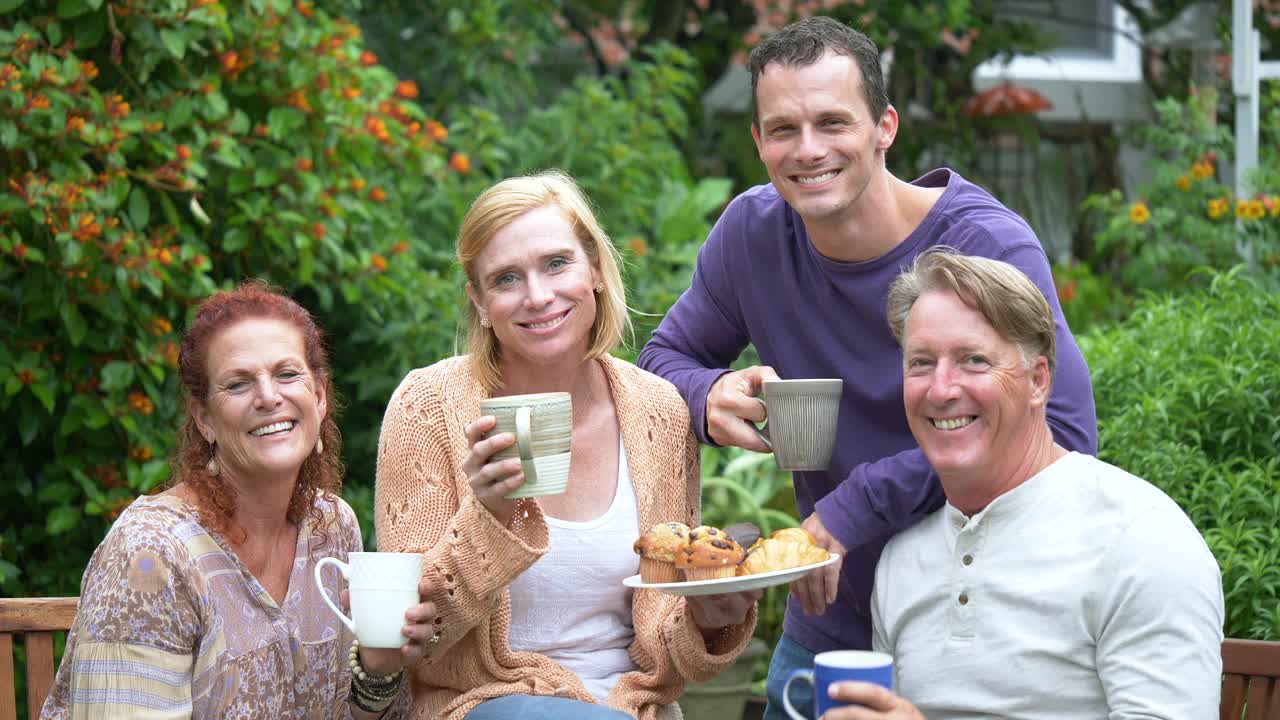 两对夫妇在后院喝咖啡，吃东西，对着镜头微笑视频素材