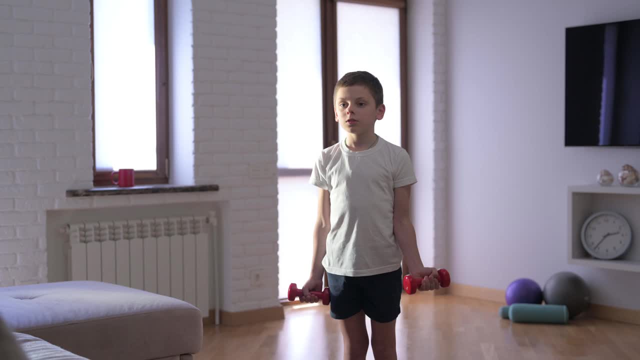 强壮活跃的白人小男孩在室内举重哑铃在家庭运动训练娱乐健身锻炼视频下载