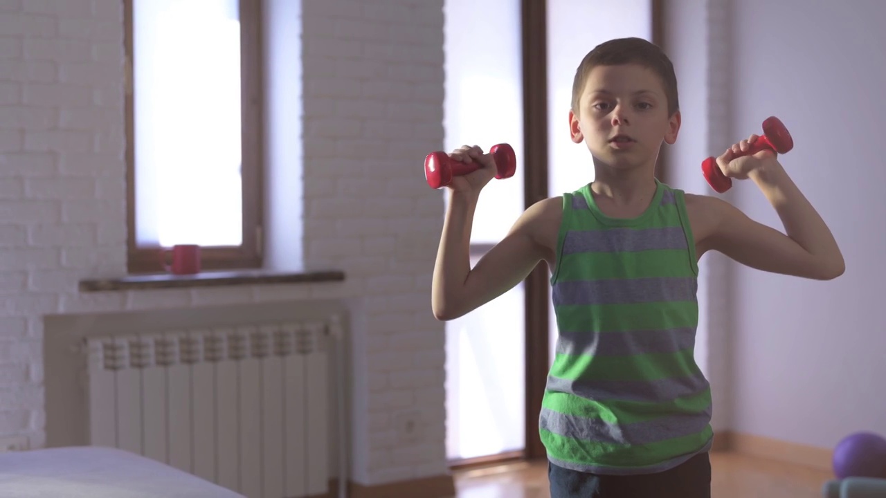 健康的小男孩在明亮的室内室内举哑铃在运动健身训练视频下载