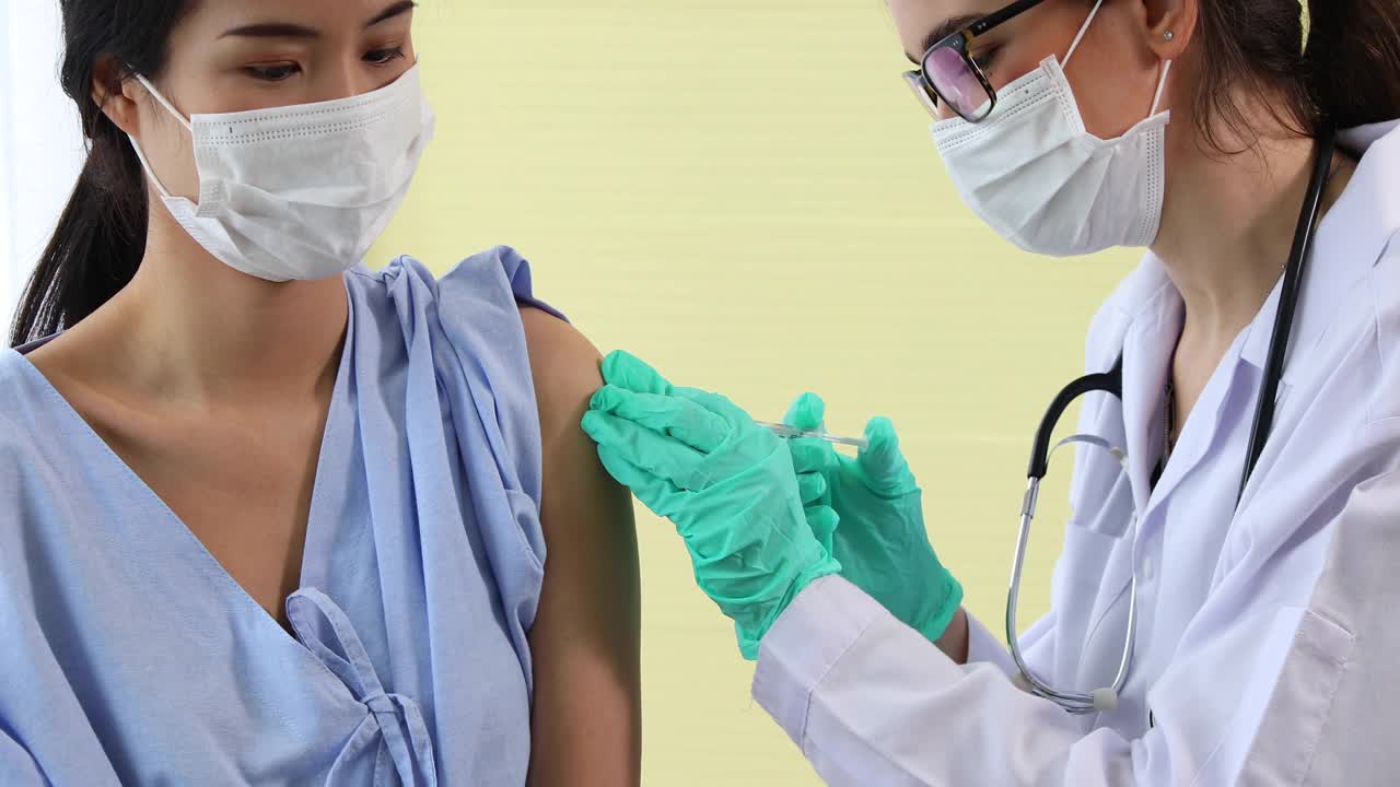 女医生拿着注射器给病人注射疫苗。年轻的亚洲妇女坐在医院里接种冠状病毒疫苗视频素材