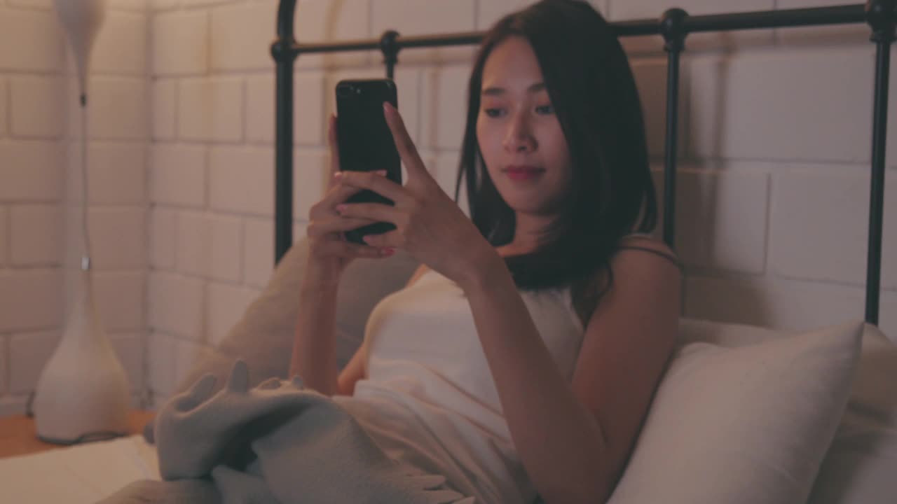 女人在晚上用手机和男朋友聊天。社交媒体上的在线约会。与人沟通。视频素材