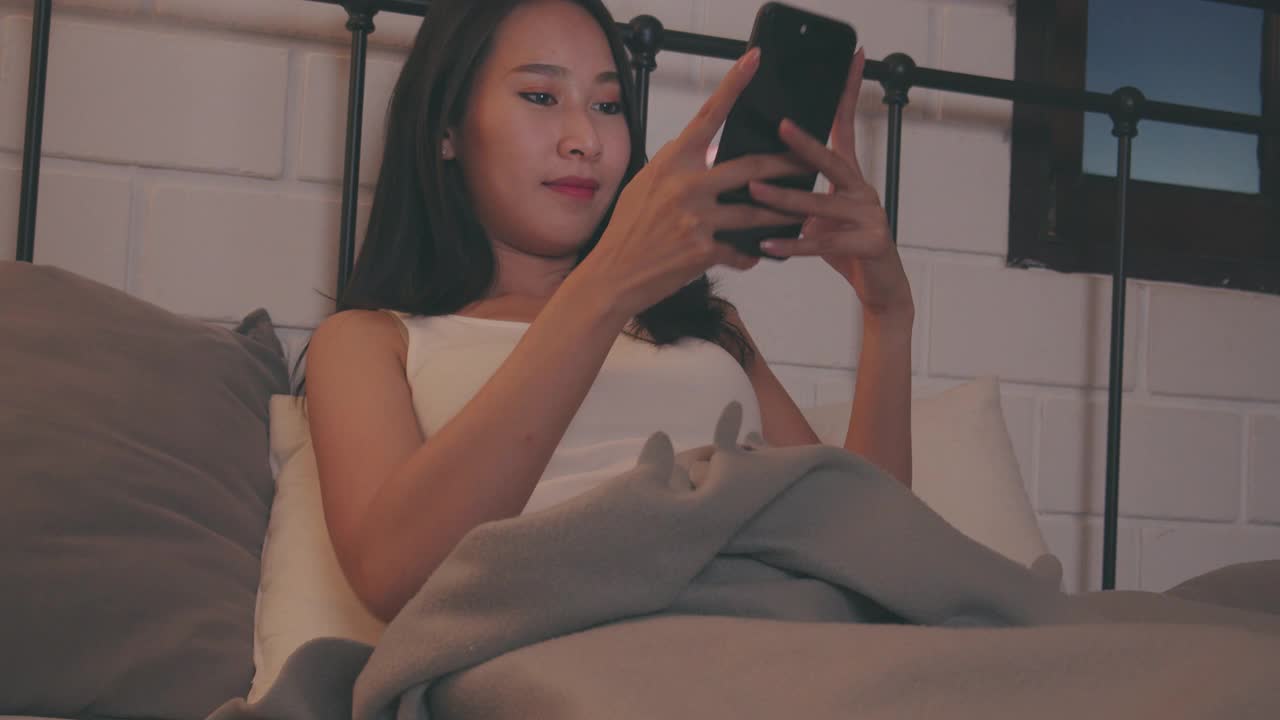 微笑的成年女子在线约会手机应用通过智能手机在晚上。视频素材