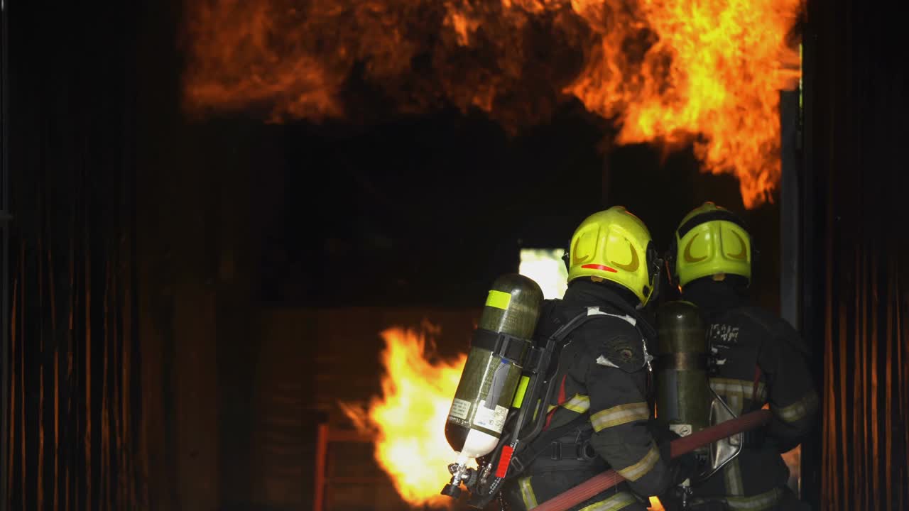 消防队员用消防水龙带扑灭正在燃烧的建筑物火灾视频素材
