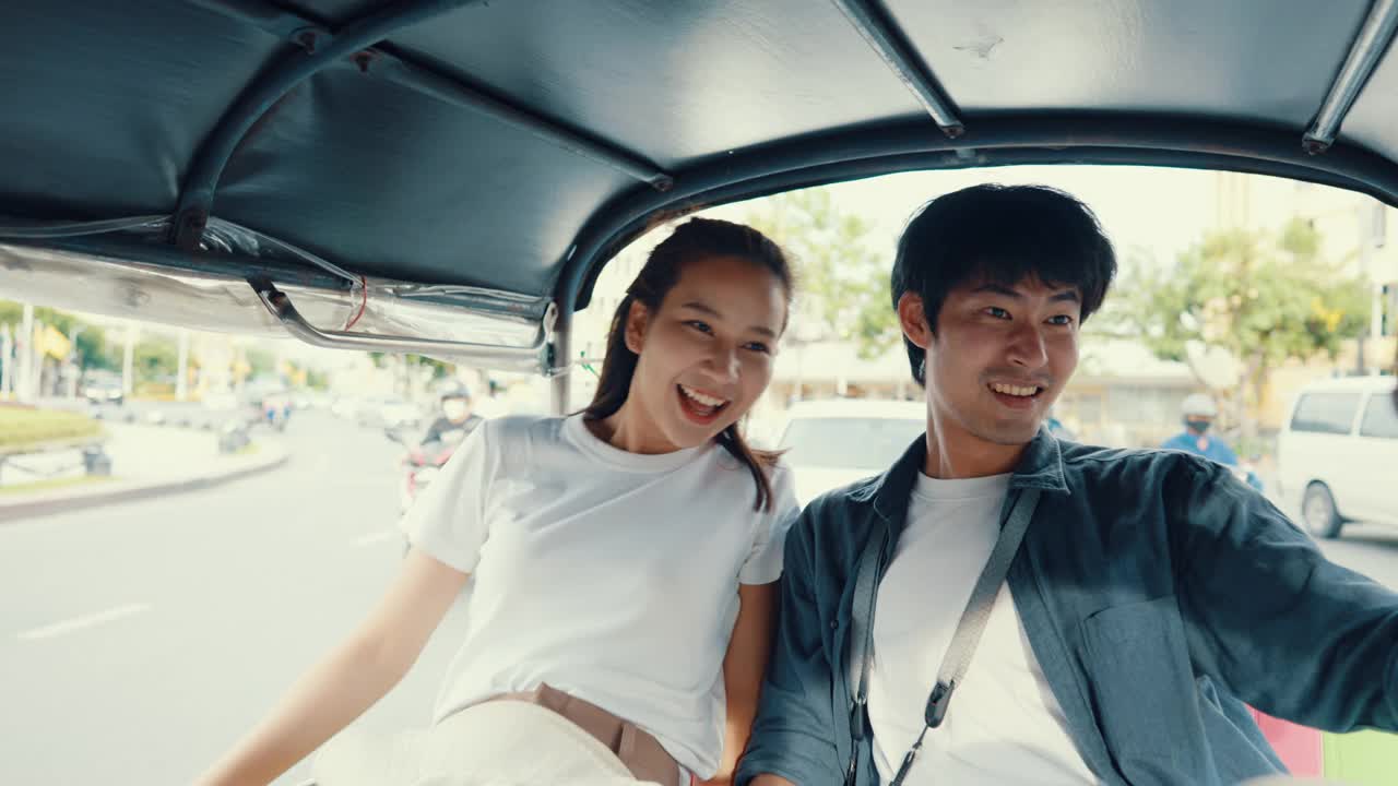 一对部落客在曼谷的地标建筑享受乘坐嘟嘟车旅行。视频下载