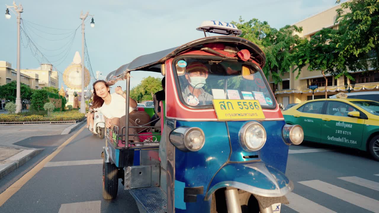 一对年轻夫妇在嘟嘟车上享受城市风景。视频下载