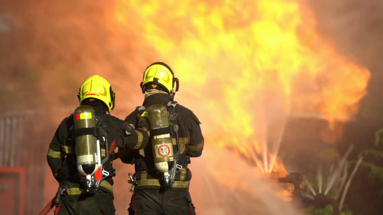 慢动作勇敢的消防员与燃烧的火焰战斗视频素材