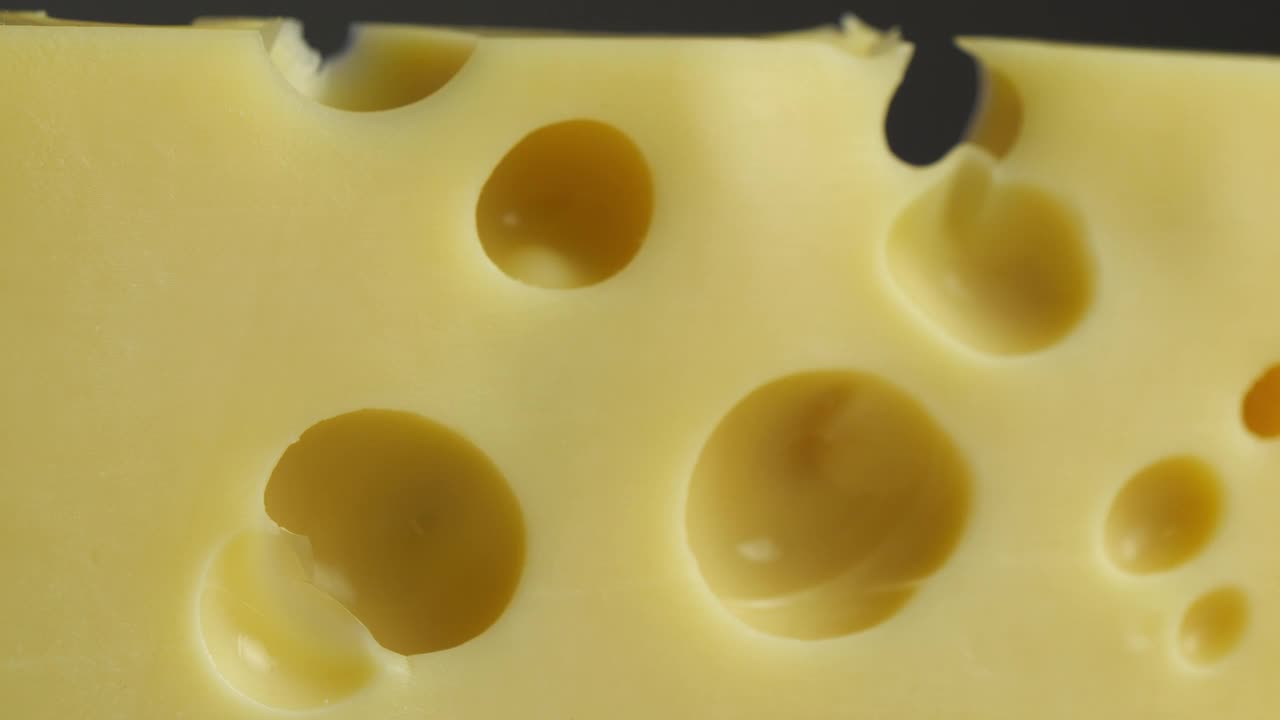 瑞士奶酪与孔靠近，奶酪旋转在慢动作背景视频视频素材