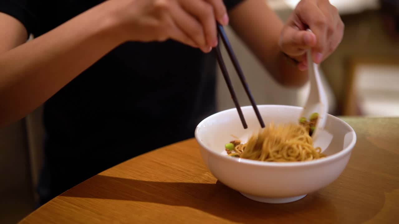 妇女一边搅拌一边用筷子吃炸酱面视频素材