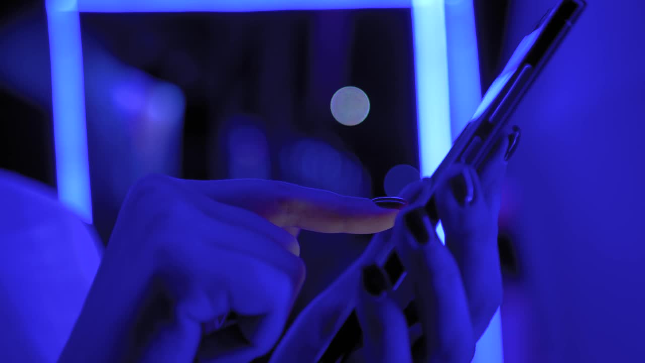 在展览中使用蓝色照明智能手机的妇女-近距离的侧视图视频素材