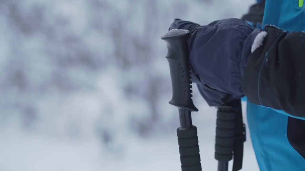 滑雪者穿着暖和的夹克，戴着手套，拿着黑色的滑雪杆视频素材