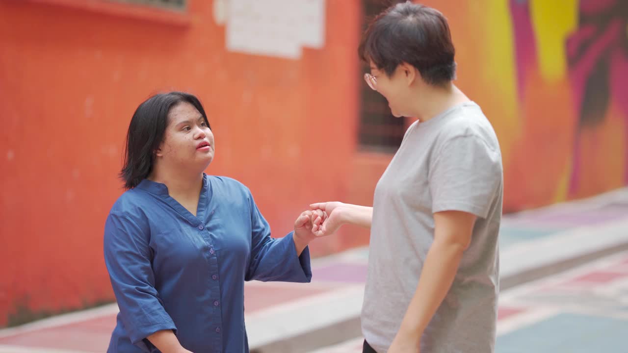 快乐的亚洲马来自闭症唐氏综合症女性与她的朋友在城市街道跳舞视频素材