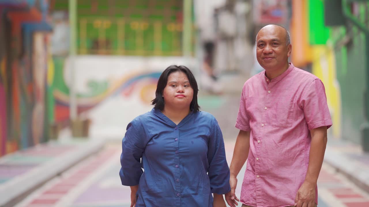 快乐的亚洲马来人自闭症唐氏综合症女性与她的父亲在城市街道视频素材