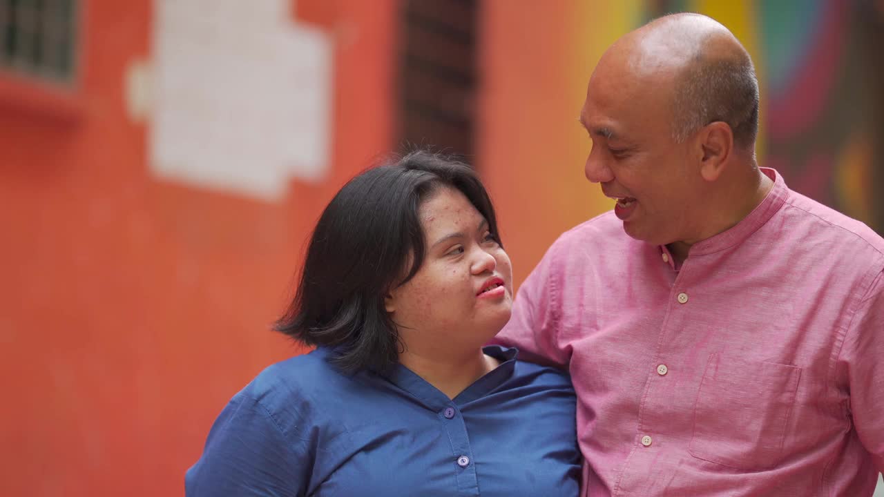 快乐的亚洲马来人自闭症唐氏综合症女性与她的父亲在城市街道视频素材