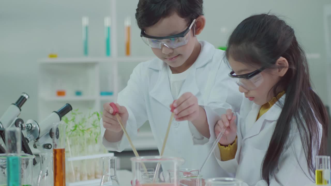 科学实验室里的亚洲孩子们正在学习如何从实验中获得乐趣。用干冰和水混合，产生凉爽的蒸汽视频下载