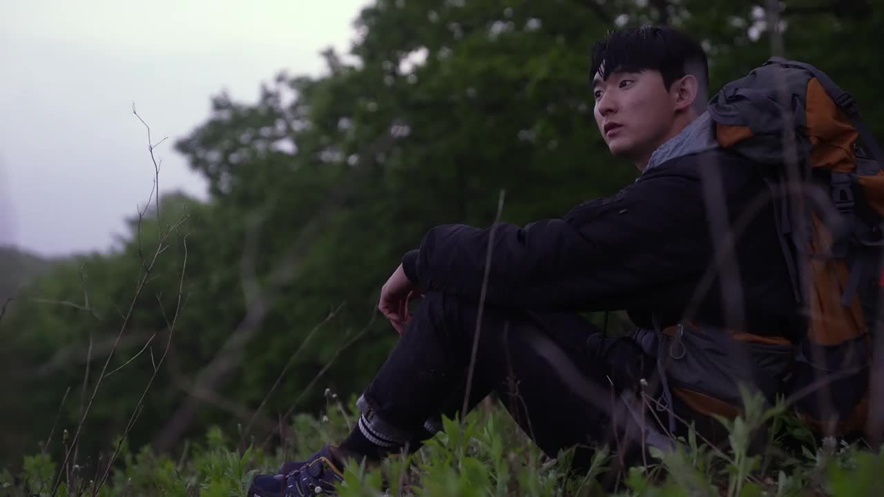 背包客——在韩国江原道江陵市安班德基村休息的年轻男子视频下载