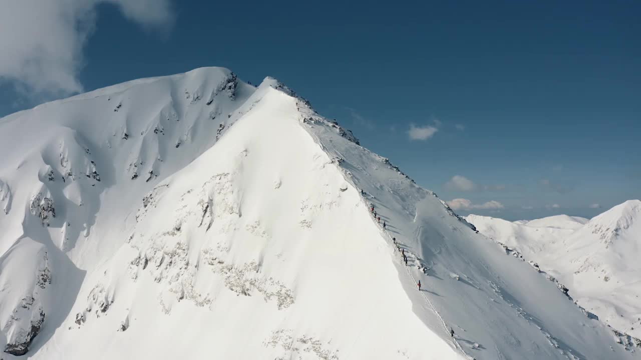 一组滑雪者和滑雪板攀登在当地滑雪胜地的雪山视频下载