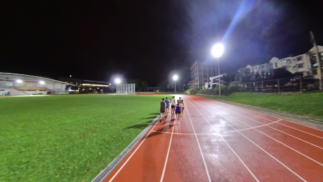夜雨天气下，亚洲中国运动员在田径场上奔跑视频下载