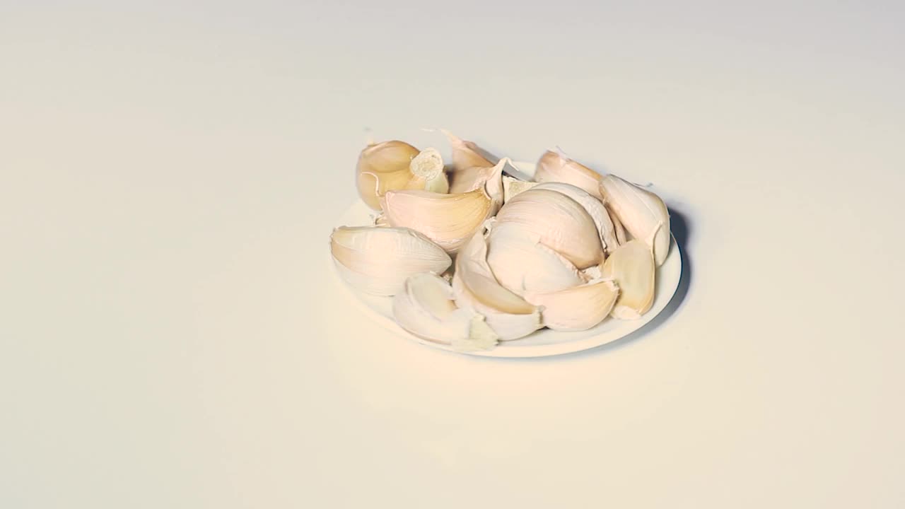 蒜瓣放在盘子里，白色的背景在周围移动。视频素材