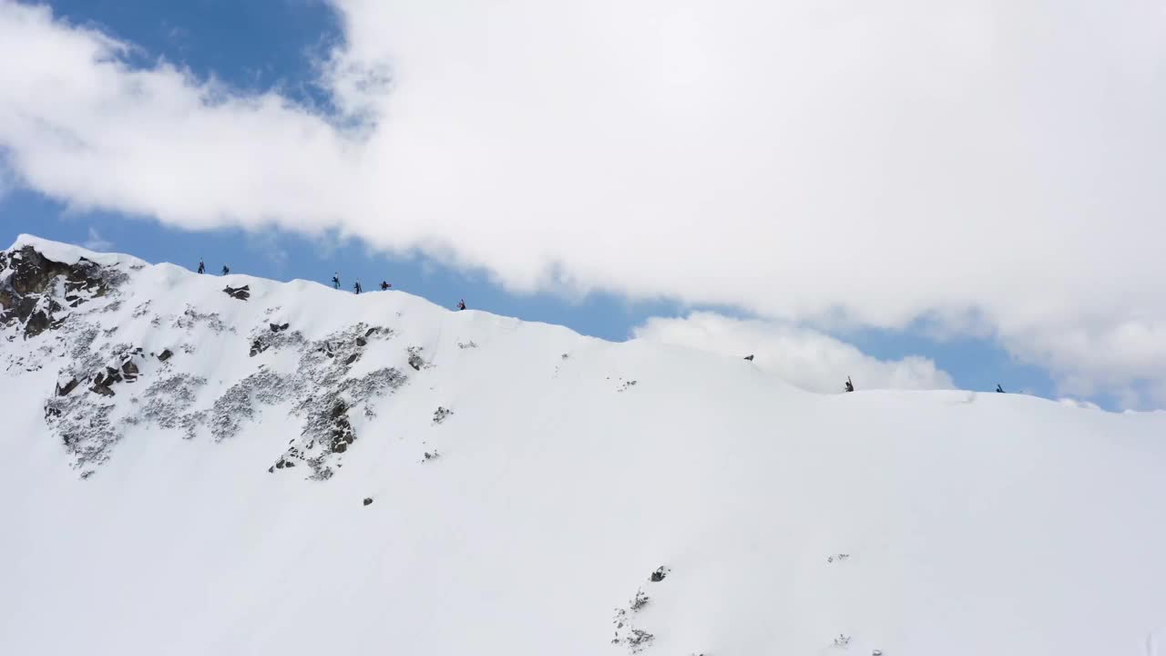 群滑雪者和滑雪板攀登美丽的山脊与壮观的山景观背后视频下载