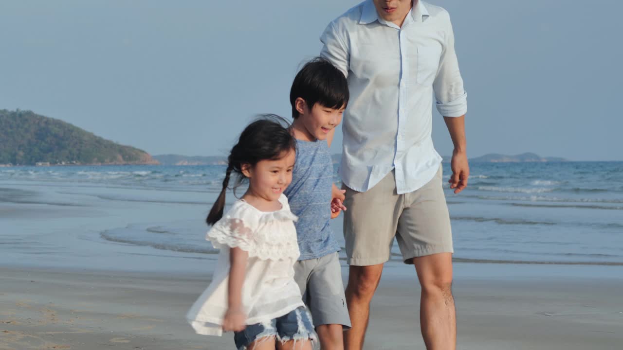 幸福的亚洲父亲家庭，男孩和女孩4-8岁手牵着手，在海边的沙滩上快乐地奔跑。积极的父母和人们在热带夏季假期户外活动的孩子。援助之手的概念。视频素材
