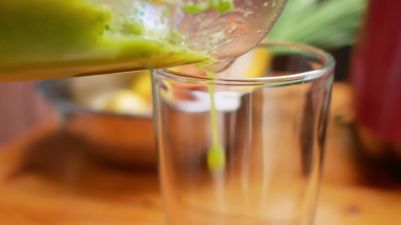 特写手把绿叶沙拉甘蓝冰沙倒进玻璃杯。健康饮食的概念。排毒和健康的生活方式。视频素材