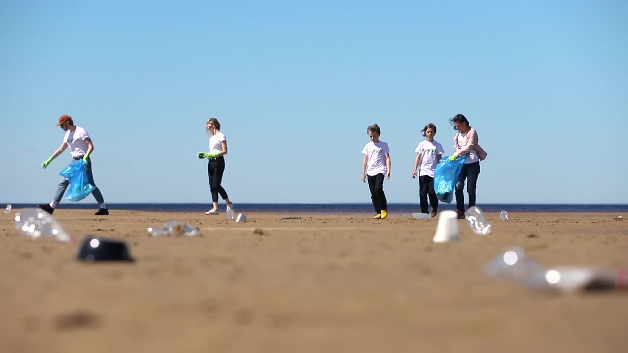 一群积极分子清理海滩上的塑料垃圾。穿着志愿者t恤的人视频素材