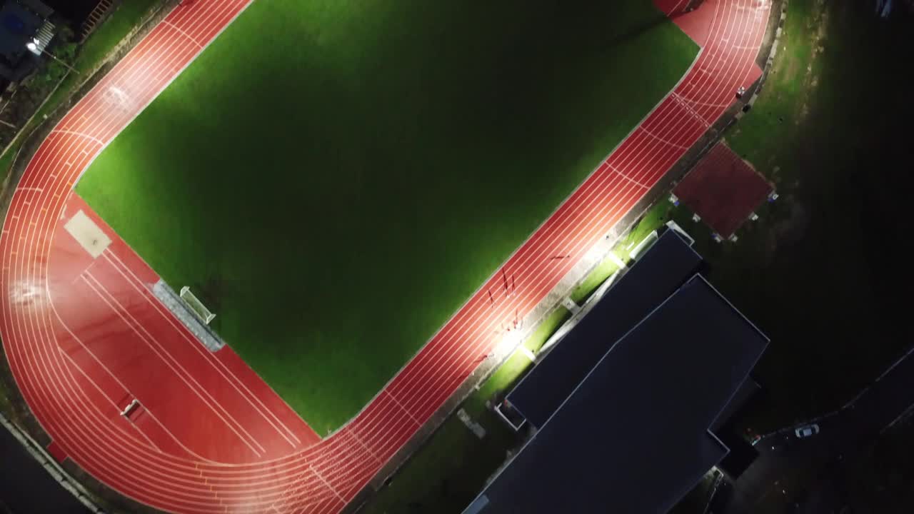 无人机在夜间直接俯瞰田径体育场视频下载