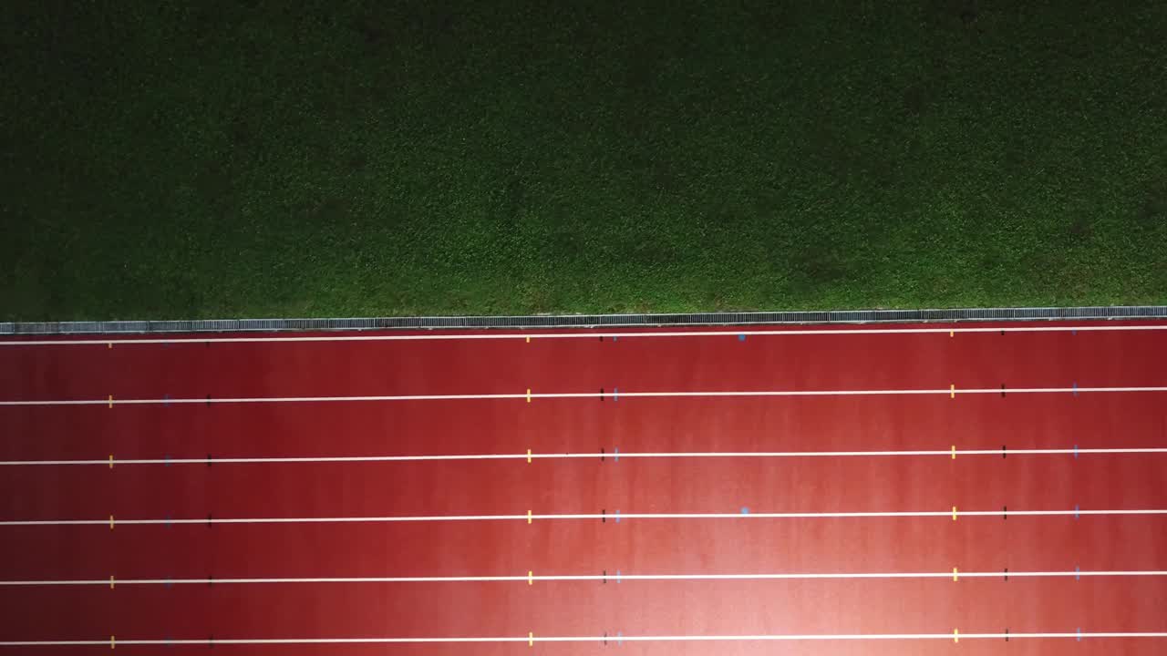 在体育场的男子跑道上，亚洲的中国男运动员在雨中奔跑视频下载