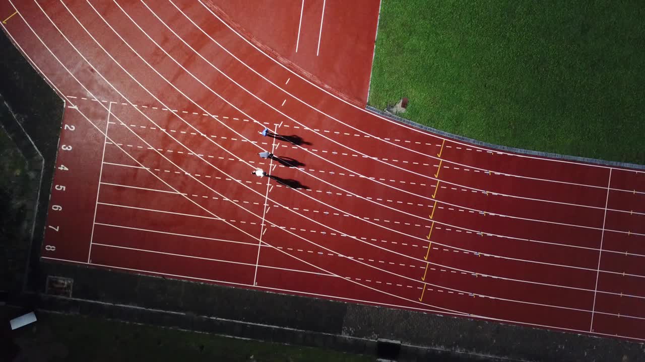 在体育场的男子跑道上，亚洲的中国男运动员在雨中奔跑视频素材