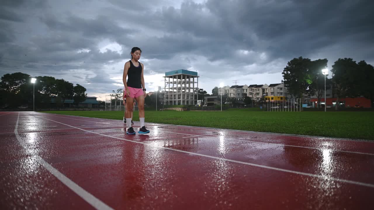 亚洲的中国女运动员在下雨的傍晚在体育场的跑道上排队跑视频素材
