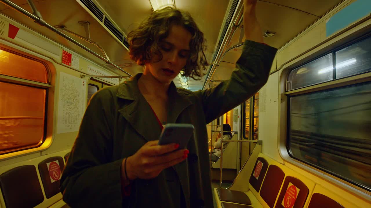 年轻的千禧一代女性在地铁里拿着智能手机视频下载