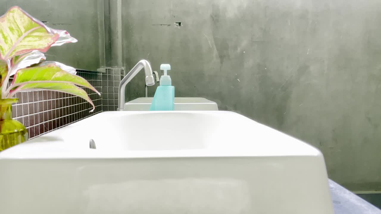 一名大个子男子在水槽边洗手，以防止在致命疫情期间感染新冠肺炎。视频下载